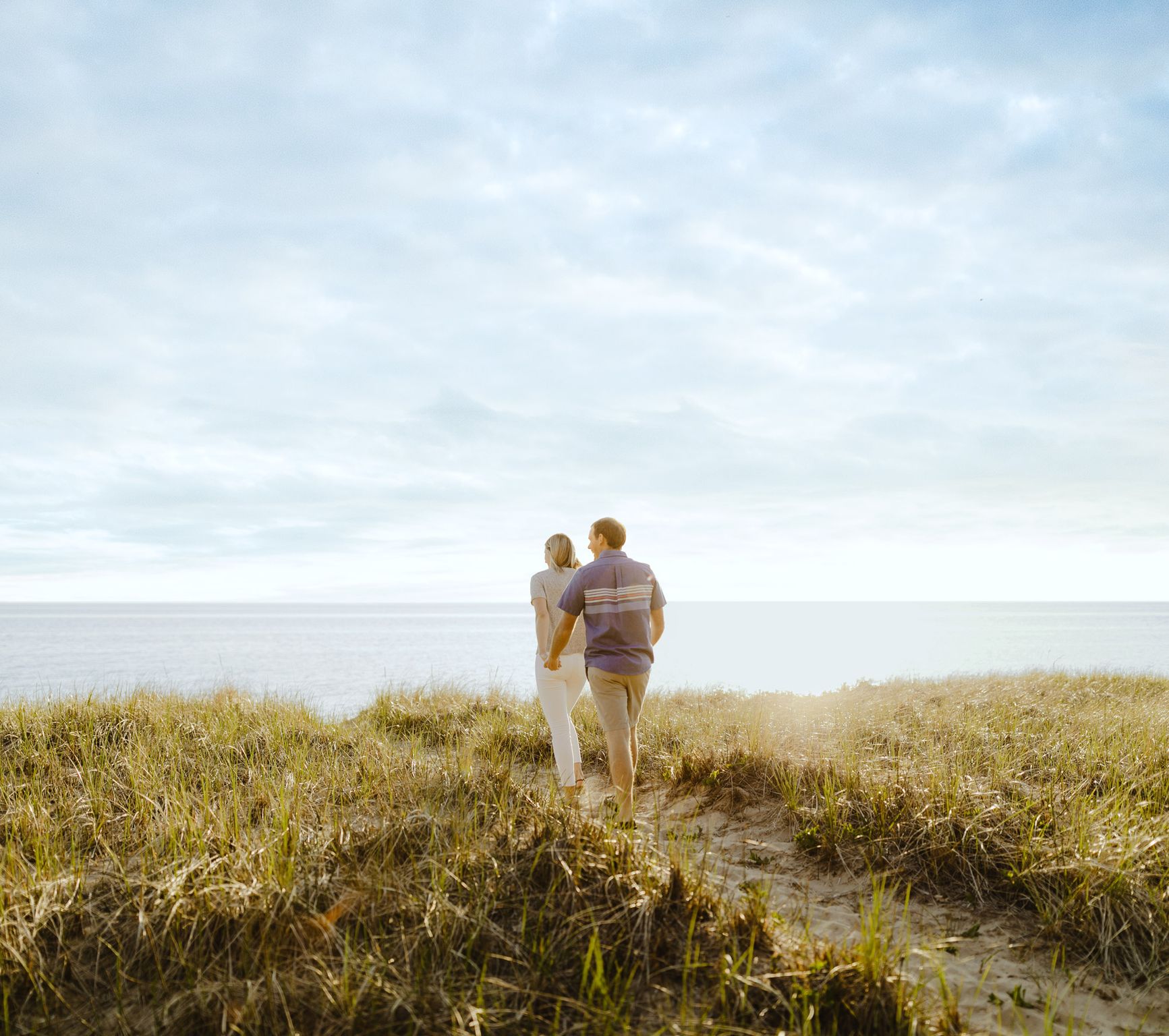 A couple walking the dune grass above Lake Michigan near Saugatuck